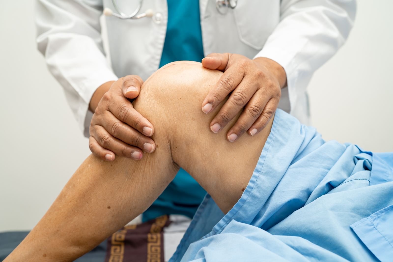 Médico examina la rodilla de un paciente en consulta