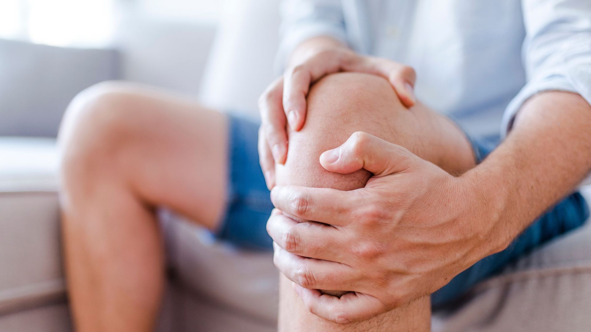 Persona con dolor de rodilla sentada en el sofá
